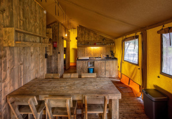 Interno di una tenda safari glamping a Holiday Park Duinhoeve, Paesi Bassi, con arredi in legno.
