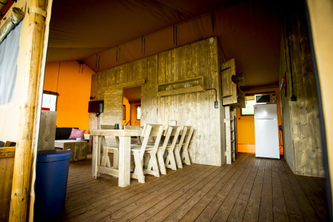 Vista interior de la tienda safari Glamping Lodge en Holiday Park Duinhoeve, Países Bajos, con muebles de madera.