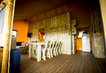 Vista interior de la tienda safari Glamping Lodge en Holiday Park Duinhoeve, Países Bajos, con muebles de madera.