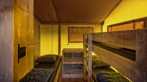 Interior de la tienda safari Glamping Lodge con literas en Holiday Park Duinhoeve, Países Bajos.