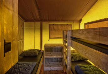 Interior de la tienda safari Glamping Lodge con literas en Holiday Park Duinhoeve, Países Bajos.