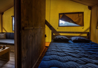 Binnenaanzicht van een Glamping Lodge safaritent met bed en zithoek bij Holiday Park Duinhoeve.