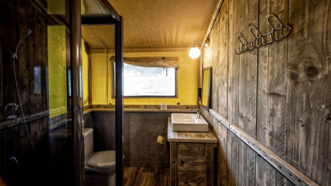 Baño dentro de una tienda safari Glamping Lodge en Holiday Park Duinhoeve, Países Bajos, con diseño rústico.