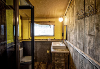 Badkamer in een safaritent Glamping Lodge bij Holiday Park Duinhoeve, Nederland, met rustiek houten interieur.