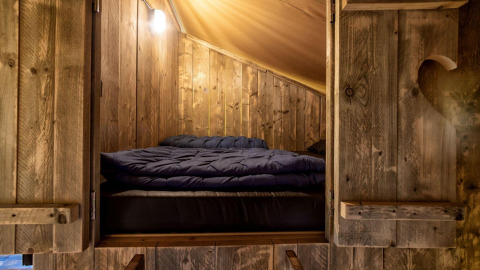 Cama acogedora en una lodge glamping de madera en Holiday Park Duinhoeve, Países Bajos, por la noche.