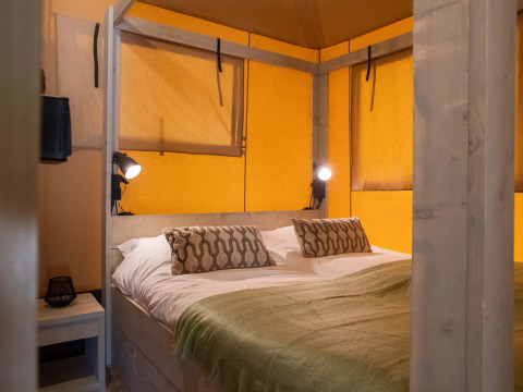 Camera da letto in una tenda safari al Holiday Park Gelloo nei Paesi Bassi, con letto matrimoniale.