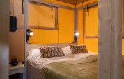 Soveværelse i en safaritelte på Holiday Park Gelloo i Nederlandene, indrettet med komfortabel seng.