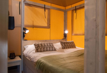 Slaapkamer in een safarietent op Holiday Park Gelloo in Nederland, met een comfortabel tweepersoonsbed.