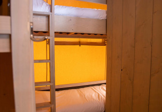 Køjesenge i en safaritelts hytte på Holiday Park Gelloo, Holland, med trævægge og orange baggrund.