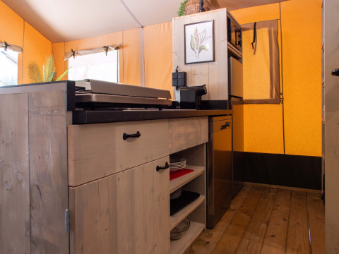 Binnenkant van een safaritent bij Holiday Park Gelloo in Nederland met houten keuken en apparatuur.