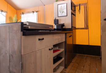 Interieur van een safaritent op Vakantiepark Gelloo in Nederland met houten keuken en apparatuur.