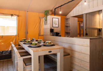 Eettafel en keuken in een luxe safaritent bij Holiday Park Gelloo in Nederland, met houten afwerking.