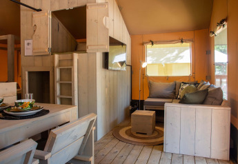 Interieur van een safaritent op Vakantiepark Gelloo in Nederland met houten meubilair en zithoek.