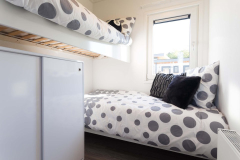 Habitación de lodge moderna con literas, ropa de cama de lunares y ventana en Z Module Wellness, Résidence Valkenburg.