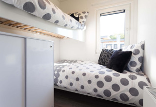 Habitación de lodge moderna con literas, ropa de cama de lunares y ventana en Z Module Wellness, Résidence Valkenburg.