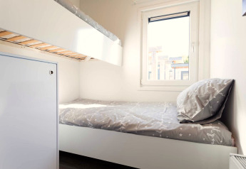 Lichte kamer met stapelbed, eenpersoonsbed, licht beddengoed, raam en moderne inrichting bij Z Module Wellness.