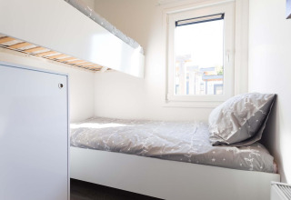 Lyst værelse med køjeseng og enkeltseng, neutralt sengetøj, vindue og moderne indretning på Z Module Wellness.