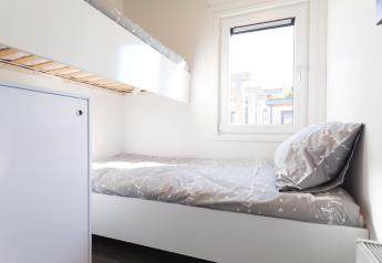 Bright room with bunk beds, single bed, light bedding, window, and modern decor at Z Module Wellness lodge.