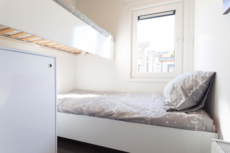 Chambre lumineuse avec lits superposés, lit simple, parure claire, fenêtre et déco moderne au Z Module Wellness.