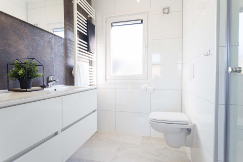 Modernes Bad mit wandhängender Toilette, großem Spiegel, Fenster und Pflanze im Z Module Wellness, Niederlande.
