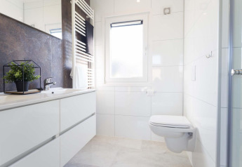 Modernes Bad mit wandhängender Toilette, großem Spiegel, Fenster und Pflanze im Z Module Wellness, Niederlande.