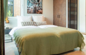 Dormitorio acogedor de lodge con cama doble, manta verde, cuadro de ciervo y decoración moderna.