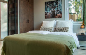 Chambre de lodge avec lit double, couverture verte, table de nuit et tableau de cerf au mur.
