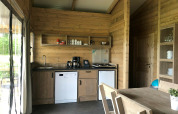 Cucina di tenda safari moderna con mobili in legno, piano cottura e lavastoviglie al Camping 't Veld nei Paesi Bassi.