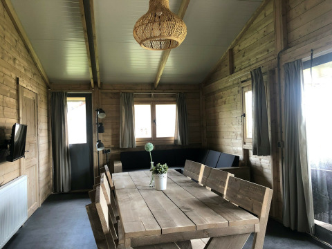 Indvendig udsigt af Tenthouse safari-teltet på Camping 't Veld i Holland med træmøbler og store vinduer.