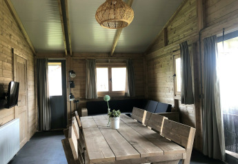Indvendig udsigt af Tenthouse safari-teltet på Camping 't Veld i Holland med træmøbler og store vinduer.