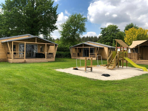 Tiendas tipo safari y parque infantil en Camping 't Veld, Países Bajos, en un día soleado.