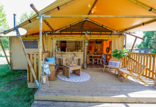 Buitenveranda en zithoek van de Dune Lodge safaritent in Sandberghe, Nederland, warm en gezellig.