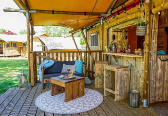 Udendørs opholdsområde ved et safariteltdesign, Dune Lodge i Sandberghe, Holland, med træmøbler.