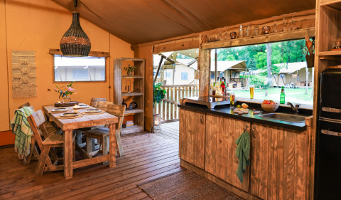 Cálida cocina y comedor en tienda safari de Dune Lodge en Sandberghe, Países Bajos, con vista exterior.