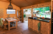 Gezellige keuken en eetruimte in een safaritent bij Dune Lodge, Sandberghe, Nederland, met buitenzicht.