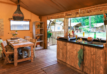 Cozy kitchen and dining area inside a safari tent at Dune Lodge, Sandberghe, Netherlands, with outdoor view.