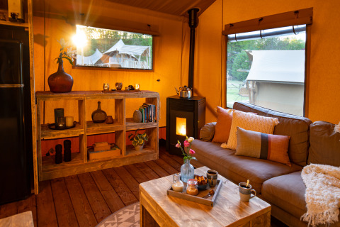 Salon chaleureux d'une tente safari au Dune Lodge, Sandberghe, Pays-Bas, avec vue et décoration rustique.