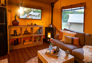 Salon chaleureux d'une tente safari au Dune Lodge, Sandberghe, Pays-Bas, avec vue et décoration rustique.
