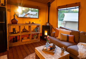 Knusse zithoek in een safaritent bij Dune Lodge, Sandberghe, Nederland, met warme sfeer en uitzicht.