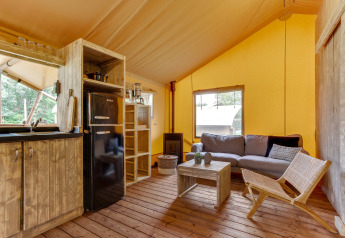 Intérieur de la tente safari Dune Lodge à Sandberghe, Pays-Bas, avec salon rustique et cuisine équipée.