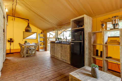 Intérieur de la tente safari Dune Lodge à Sandberghe, Pays-Bas, avec sol en bois et coin cuisine.