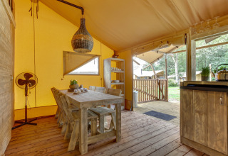 Interieur van een safaritent bij Dune Lodge, Sandberghe, Nederland, met rustieke houten meubels.