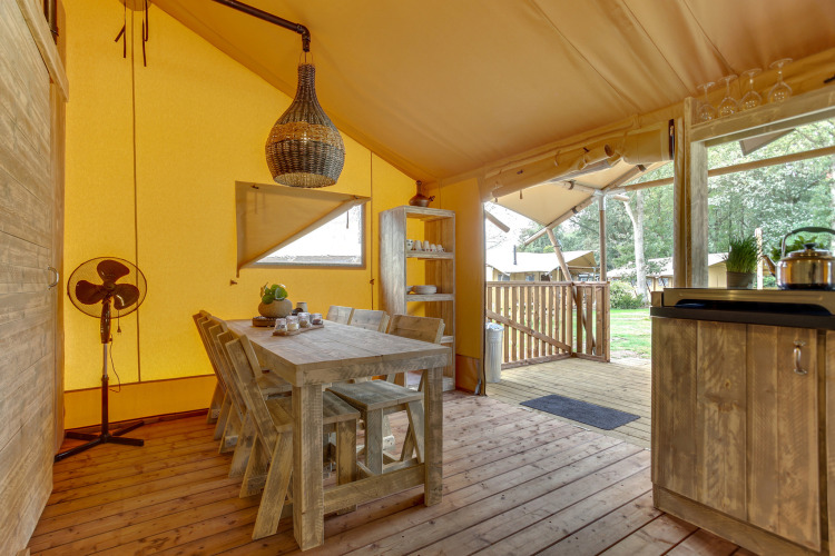 Interieur van een safaritent bij Dune Lodge, Sandberghe, Nederland, met rustieke houten meubels.