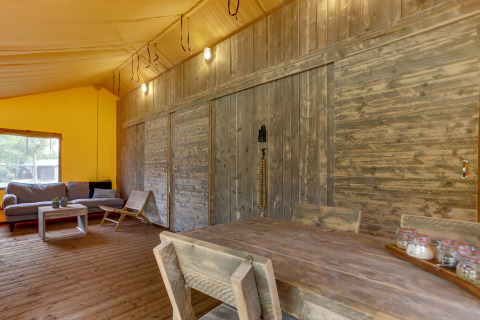 Interior de la tienda safari Dune Lodge en Sandberghe, Países Bajos, con muebles rústicos de madera y cómodo salón.