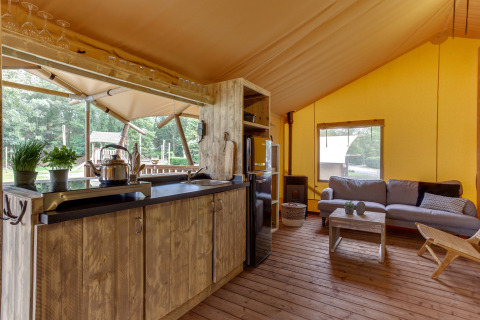 Interior de la tienda safari Dune Lodge en Sandberghe, Países Bajos, con cocina y sala de estar visibles.