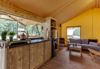 Interieur van de Dune Lodge safaritent bij Sandberghe in Nederland met keuken en zithoek zichtbaar.