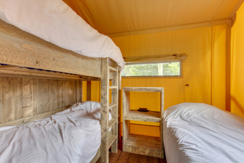 Interior de la tienda safari Dune Lodge en Sandberghe, Países Bajos, con literas y muebles rústicos.