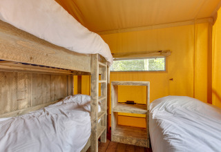 Interieur van de Dune Lodge safaritent bij Sandberghe in Nederland met stapelbedden en houten meubels.