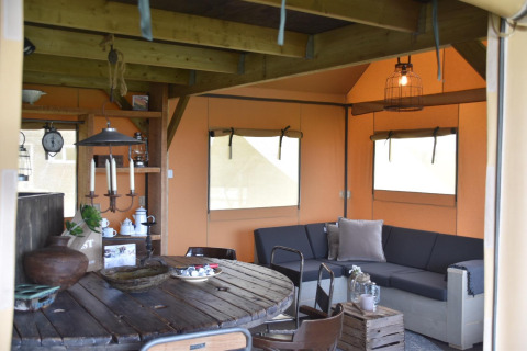 Innenansicht der Beach Lodge Big im Duynpark Het Zwanenwater mit gemütlicher Sitzecke und Holztisch.