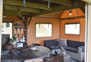 Vue intérieure de la Beach Lodge Big à Duynpark Het Zwanenwater avec mobilier rustique et canapé d’angle confortable.